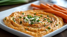 a white plate topped with carrots and hummus