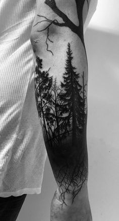 a man's arm with trees and birds on it