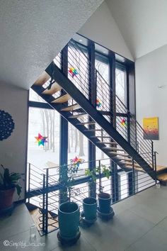 there is a stair case in the middle of this room with potted plants next to it