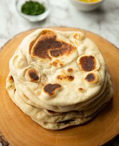 a stack of flat bread sitting on top of a wooden plate