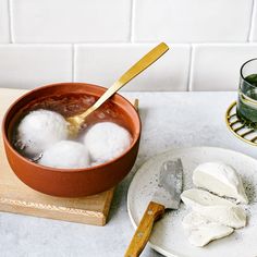 ice cream is being poured into a bowl on a wooden cutting board next to a glass of green tea