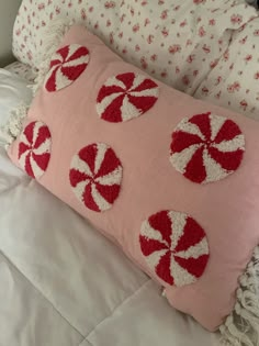 a pink pillow with red and white candy canes on it sitting on a bed