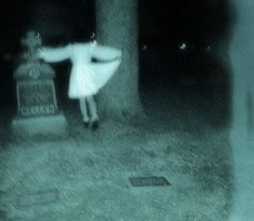 a woman in white dress standing next to a tree