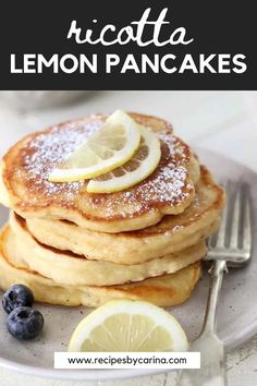 a stack of pancakes with lemon slices and powdered sugar on top