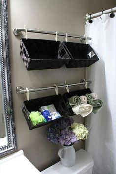 a white toilet sitting next to a bathroom sink under a mirror and hanging baskets on the wall