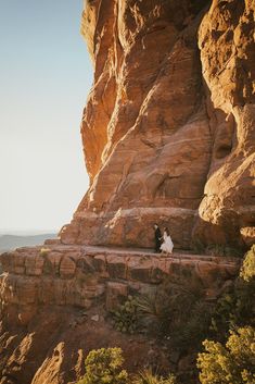 a man and woman standing on top of a cliff next to each other in the desert