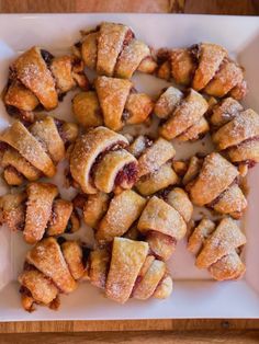 several pastries are arranged on a white plate with powdered sugar and cranberry filling