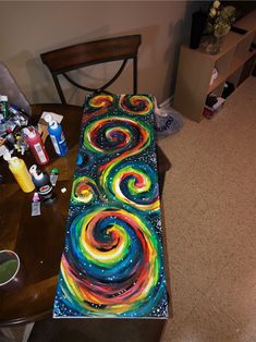 the table is covered with art supplies and has a painting on it that looks like swirling swirls