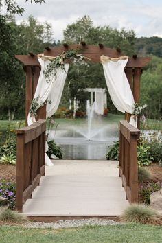 an outdoor wedding ceremony set up with white drapes and greenery on the steps