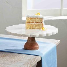 a piece of cake sitting on top of a white cake plate next to a blue table cloth