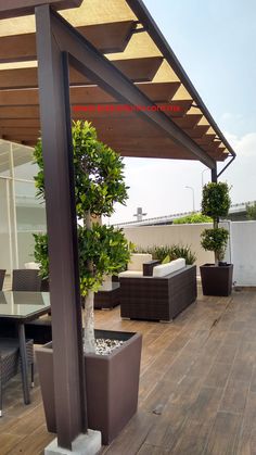 an outdoor patio with wooden flooring and furniture on the roof top deck, surrounded by potted trees