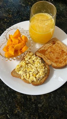 a white plate topped with toast and fruit next to a glass of orange juice on top of a table