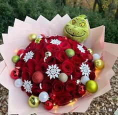 a bouquet of red roses and ornaments with a grin face on it's head