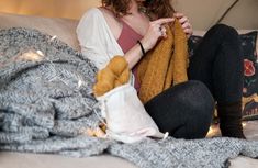 a woman sitting on top of a couch next to a pile of blankets