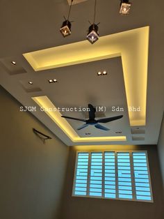 a ceiling fan in the middle of a room with windows and lights on either side