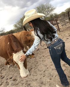 a woman in cowboy hat petting a cow