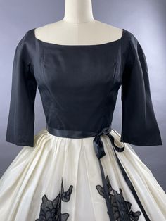 LATE 1950s SUZY PERETTE Black and White party dress with stunning black floral appliques. With a fitted bodice in a deep black taffeta she has a wide, very slightly squared neckline which is extremely flattering. Her bodice is fitted and she has elbow length sleeves. Her skirt is generous and is an organza layer over a matching lining. She features four appliques in a slightly translucent black which depict a rose and leaves. She has a plunging deep v neckline to the back and fastens with a cent Black Dress With Fitted Bodice For Vintage Events, 1950s Evening Dresses With Fitted Bodice, Black Fitted Dress For Vintage Events, Fitted Black Dress For Vintage Events, 1950s Style Black Dress For Vintage Events, Fitted Black Dress In 1950s Style, 1950s Black Vintage Evening Dress, Black Fitted 1950s Style Dress, 1950s Style Black Vintage Dress