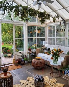 a sun room with wicker furniture and flowers in the vases on the table