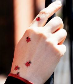 a ladybug tattoo on the wrist of a woman's left hand,