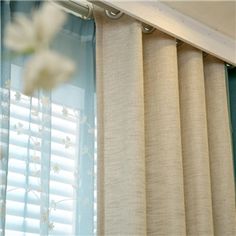 the curtains are closed in front of the window with flowers hanging from it's rod