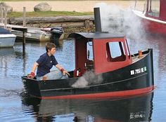 a man in a red and black boat with steam coming out of the front end