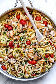 a skillet filled with pasta, shrimp and cherry tomatoes