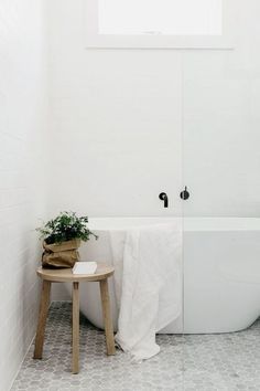 a white bath tub sitting next to a wooden stool