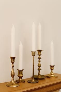 brass candlesticks are lined up on a mantle