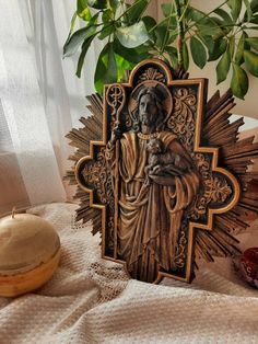 a statue of jesus holding a child on top of a table next to a potted plant