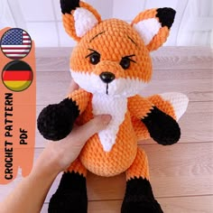 an orange and black knitted fox sitting on top of a wooden table with the words english crochet pattern pop + video below it