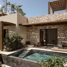 a house with a pool in front of it and stone walls on the outside wall