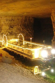 the entrance to a cave lit up at night with lights on it's sides