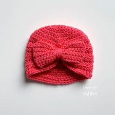 a pink crocheted hat with a bow on it's brimmed