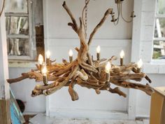 a chandelier made out of driftwood sticks and lit candles in a room