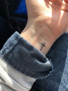 a person with a small cross tattoo on their wrist