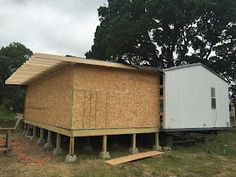 a house that is being built in the middle of some grass with trees behind it