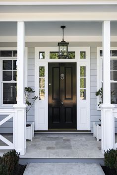 the front door of a gray house with white pillars