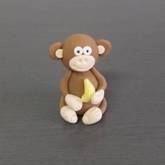 a small toy monkey sitting on top of a gray table with a banana in it's mouth