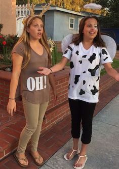 two women standing next to each other in front of a brick wall with the word oh on it