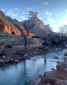 a river running through a lush green forest filled with trees and rocks next to mountains