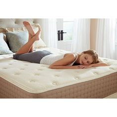 a woman laying on top of a mattress in a bedroom