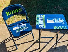 two chairs and table sitting on the side walk in front of a grassy area with grass