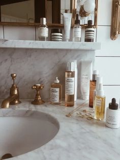 a marble sink with gold faucet, soap and lotion bottles on it