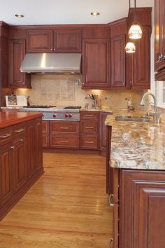 a large kitchen with wooden cabinets and marble counter tops, along with hardwood flooring