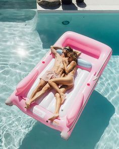 a man and woman laying on an inflatable raft next to a swimming pool