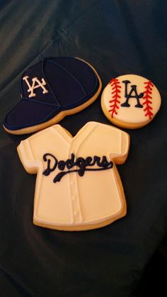 three cookies decorated like baseballs and shirts with the word dodgers written in blue on them