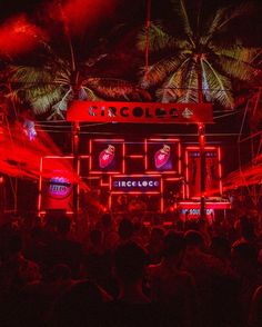 a large group of people standing in front of a building with neon lights on it