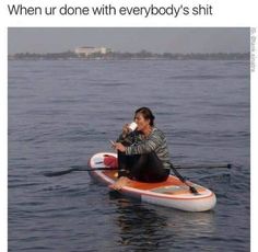 a woman sitting on top of a kayak in the water drinking from a cup