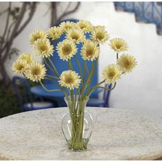 a vase filled with yellow flowers sitting on top of a table next to a blue chair