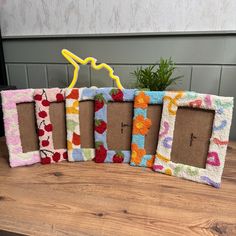 four colorful frames are sitting on a table with a potted plant in the middle